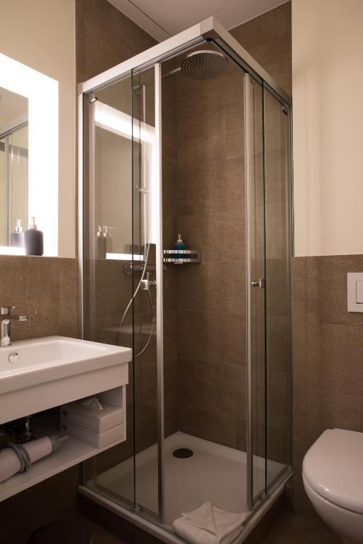a bathroom with a shower with a sink and a toilet at Kreuz Bern Modern City Hotel in Bern