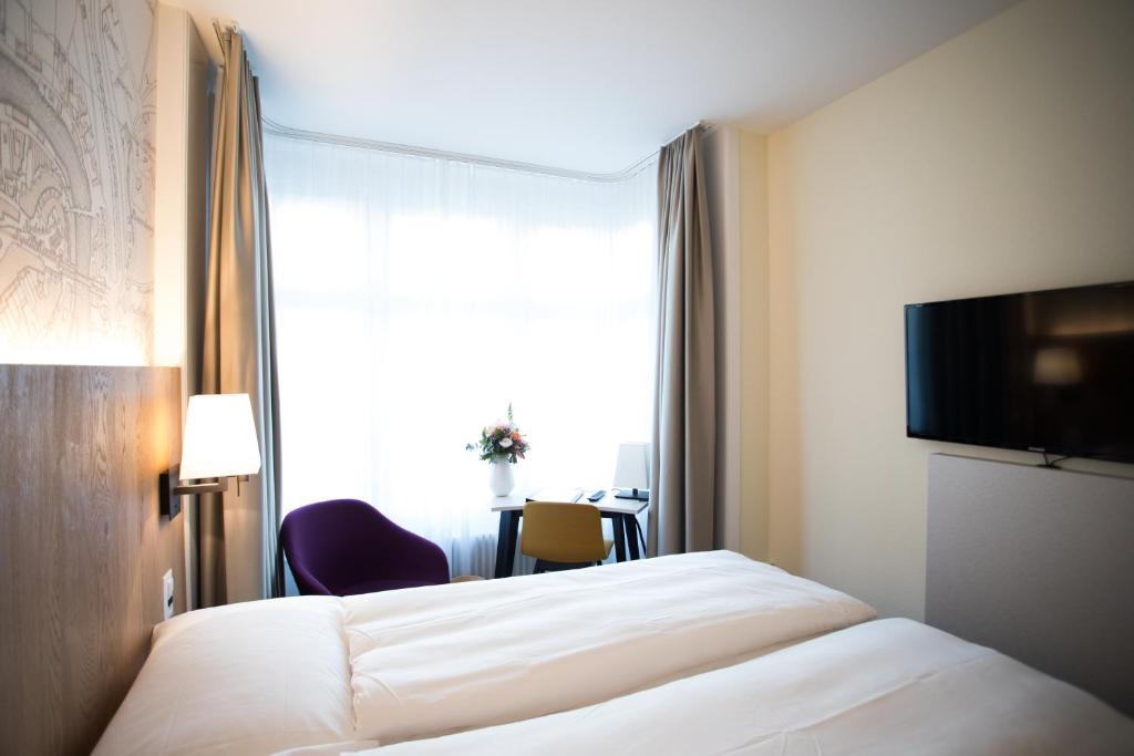 a hotel room with a bed and a window at Kreuz Bern Modern City Hotel in Bern