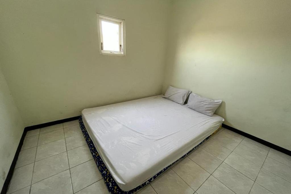 a white bed in a room with a window at OYO Life 92982 Kost Berkah Ibu in Lawang