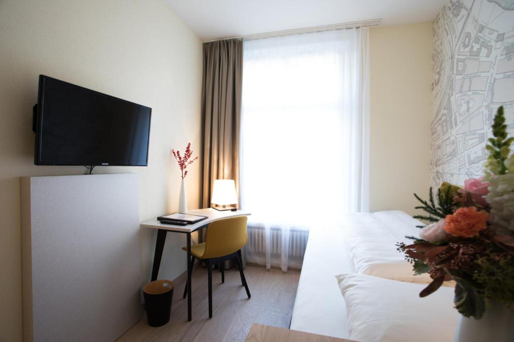 a living room with a couch and a table and a tv at Kreuz Bern Modern City Hotel in Bern