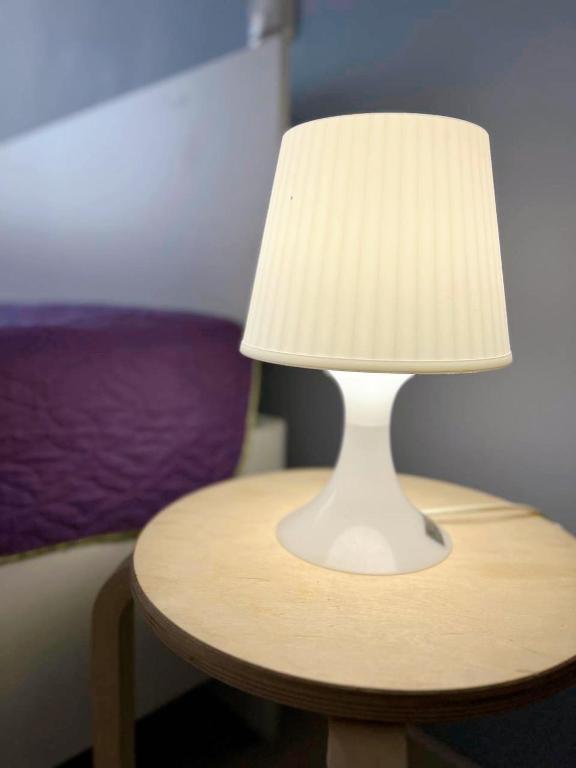 a white lamp on a table next to a bed at Sunny Home in Oral