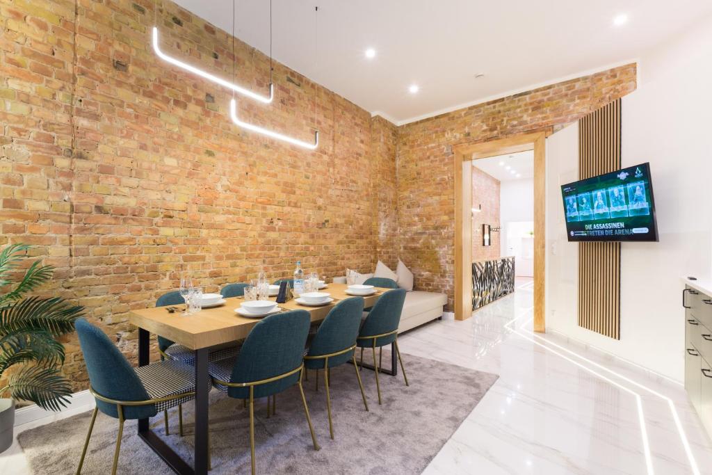 a dining room with a brick wall and a table and chairs at Hevals Spa & Design Apartment in Berlin