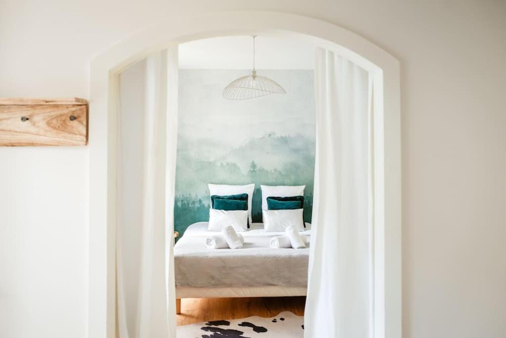 une chambre avec un lit blanc avec des oreillers bleus dans l'établissement L'appart' du dessous, à Gérardmer