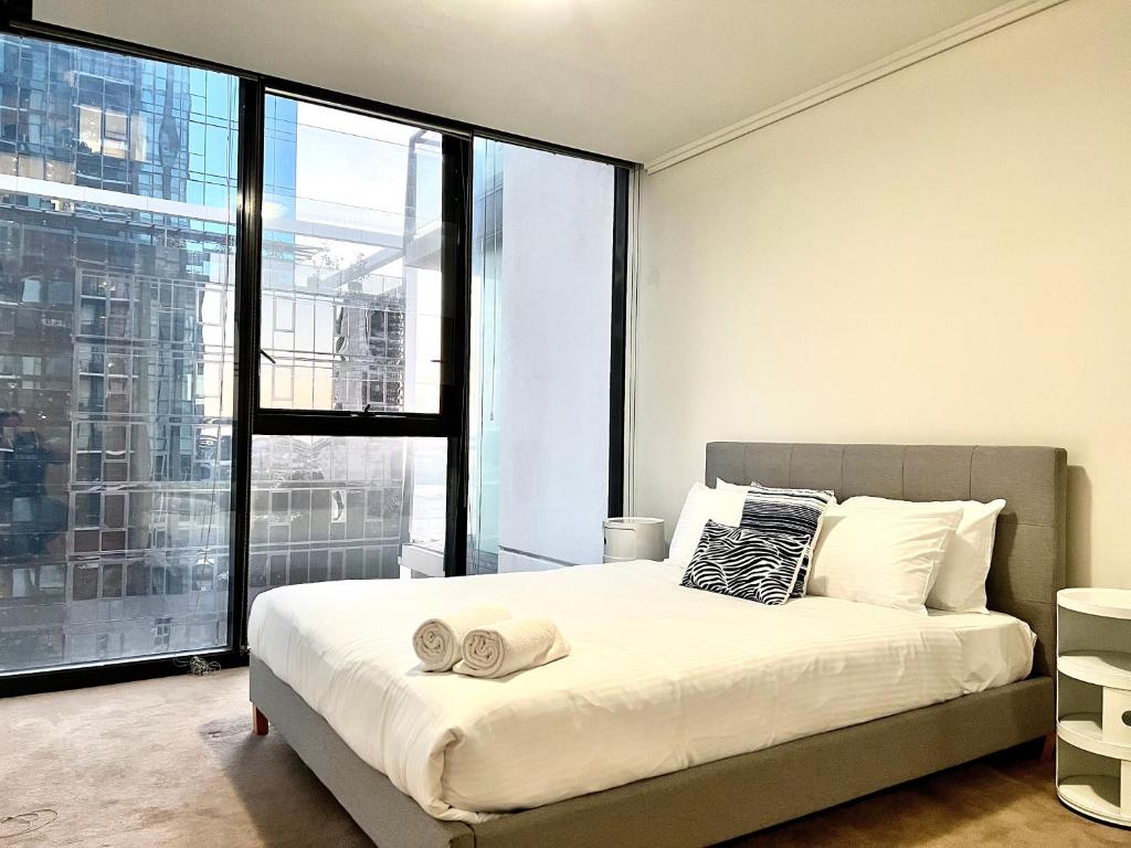 Un dormitorio con una cama y una ventana grande. en ReadySet Apartments at Sentinel, en Melbourne