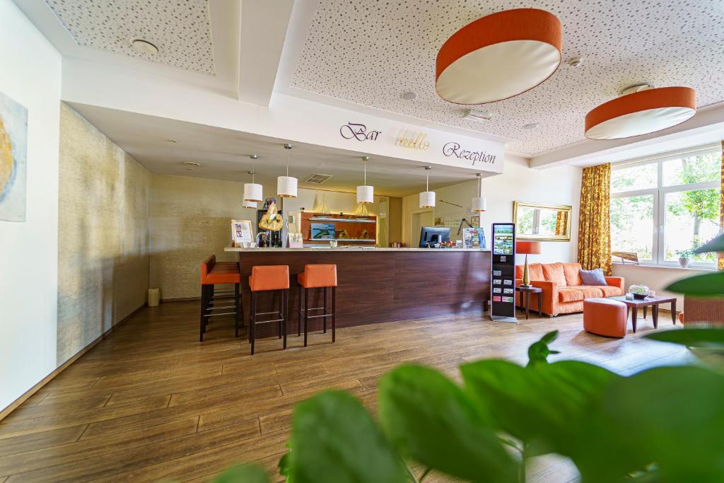 uma ampla sala de estar com um bar e cadeiras em Einklang - Dein Hotel am Südhorn em Wendisch Rietz