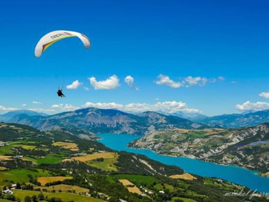 a paraglider flying in the sky over a lake at Chez Pierrette et Eugène Prix nuitée&#47;10 personne in Le Lautaret