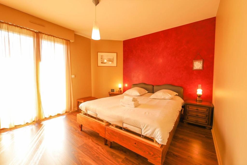 sypialnia z dużym łóżkiem z czerwoną ścianą w obiekcie La Pause annécienne appartement familial w Annecy
