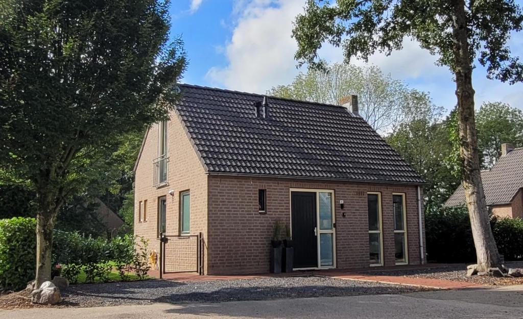 een klein huis met een zwart dak bij Evergreen wellness met sauna & hottub in Ewijk