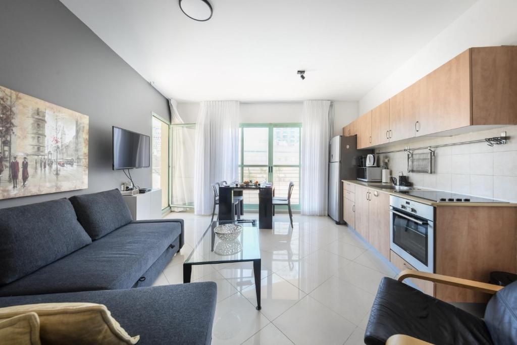 ein Wohnzimmer mit einem Sofa und einer Küche in der Unterkunft Elegant Sea-View Apartment with Mamad in the Heart of Tel Aviv by Sea N' Rent in Tel Aviv