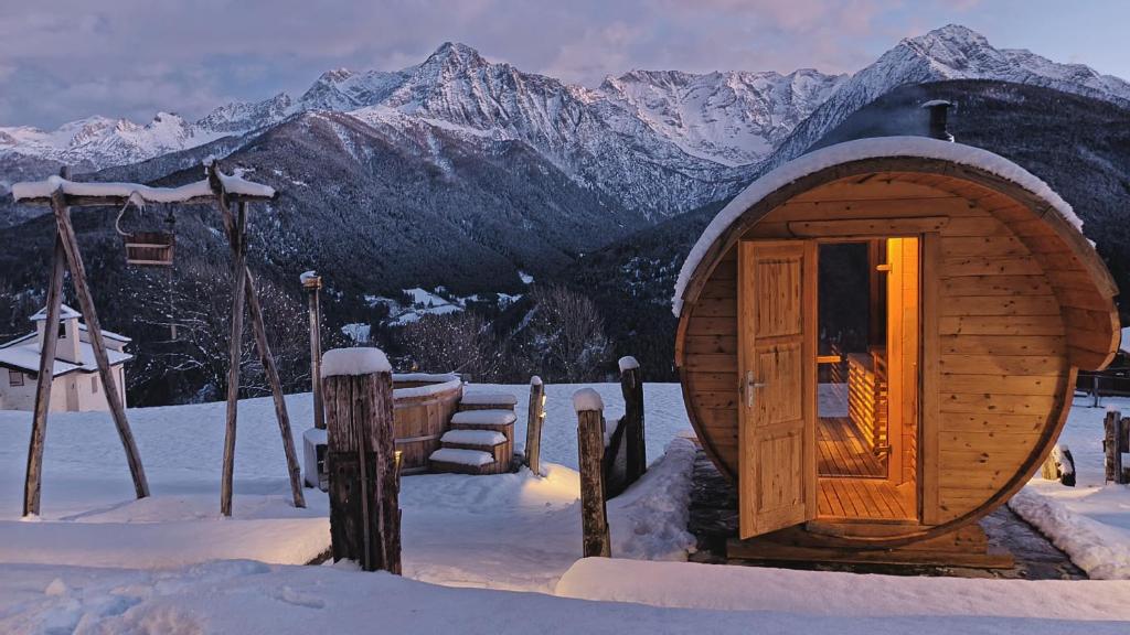 Cabaña de madera pequeña en la nieve con montañas en Chalet Cormignano, en Vezza d'Oglio
