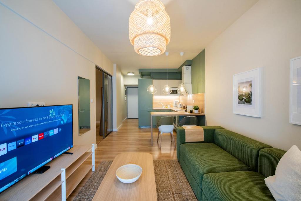 a living room with a green couch and a flat screen tv at Mandarin apartments by halu! in Thessaloniki