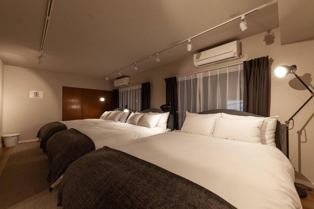 a hotel room with two beds with white pillows at Maison Roppongi in Tokyo