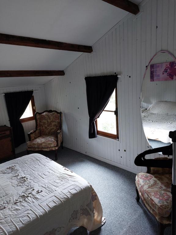 a bedroom with a bed and a chair and window at La Quiétude in Cotignac