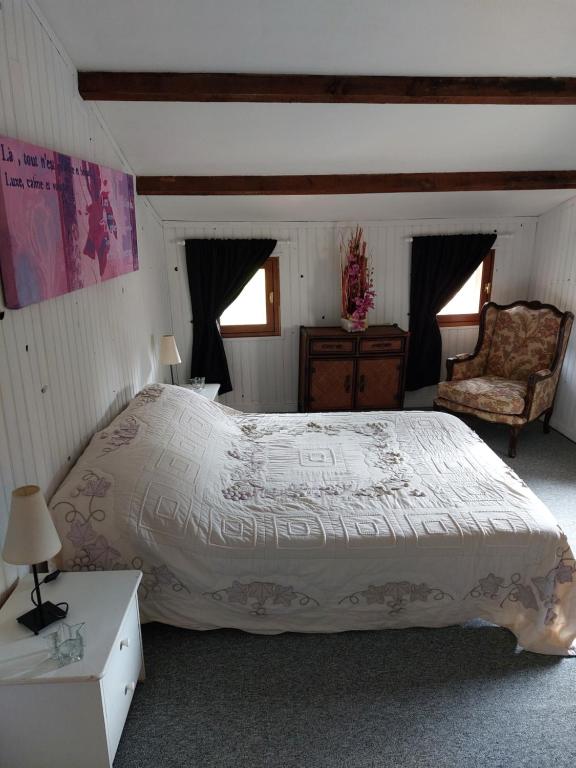 a bedroom with a large bed and a chair at La Quiétude in Cotignac