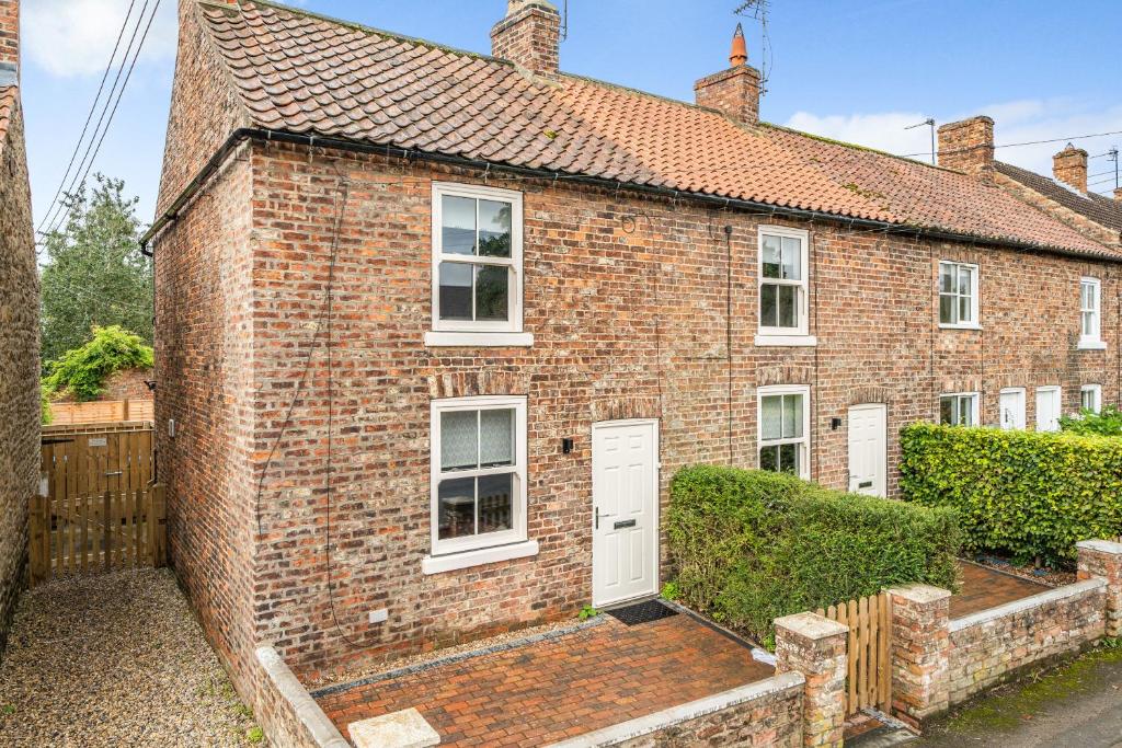 a brick house with a white door and a fence at East End Cottage - Herriot Country in York