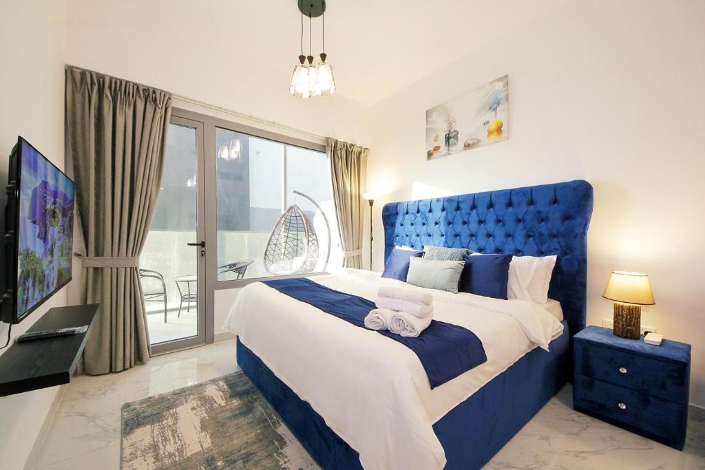 a bedroom with a blue bed and a balcony at Silk Valley - Furnished Studio With Balcony in Abu Dhabi