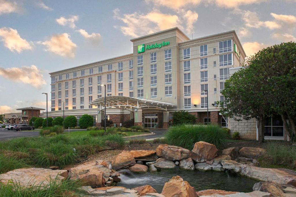 a hotel building with a creek in front of it at Holiday Inn Ardmore, an IHG Hotel in Ardmore