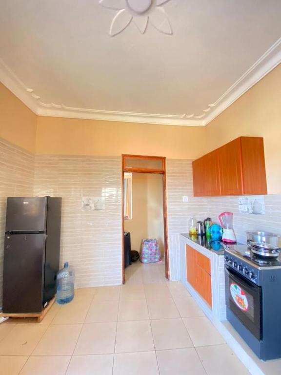 eine Küche mit einem schwarzen Kühlschrank und einem Herd in der Unterkunft Blessings apartment buziga in Kampala