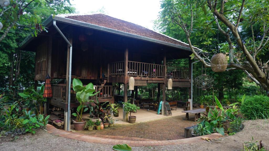 a wooden house with a deck in the forest at Traditional Lanna house near hot spring in Chiang Dao