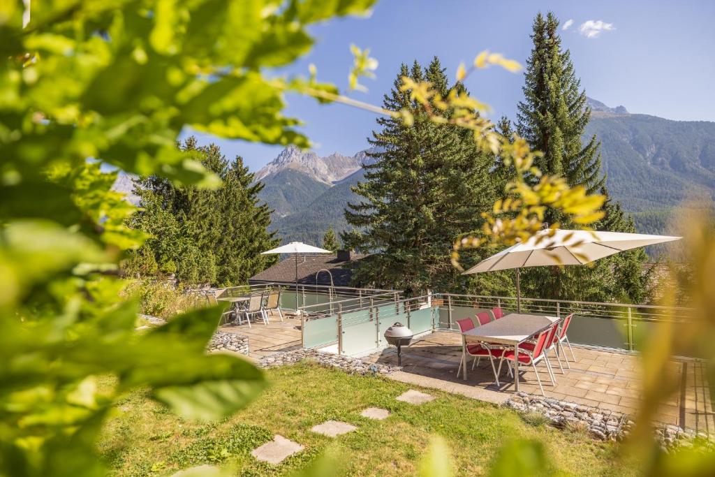 a patio with a table and chairs and an umbrella at Arch San Martin B in Scuol