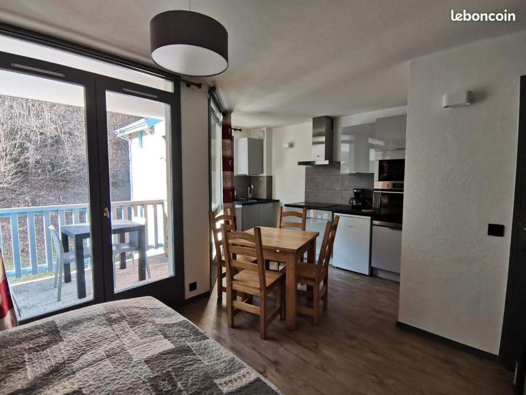 une cuisine et une salle à manger avec une table et un balcon dans l'établissement Studio au Cœur de la Tarentaise, à La Lechere