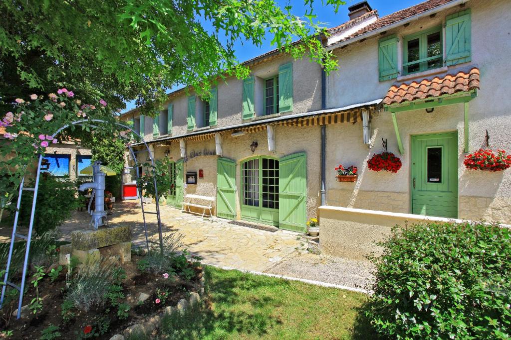 une maison avec des portes vertes et une cour dans l'établissement Le Clos Grand, à Pradines