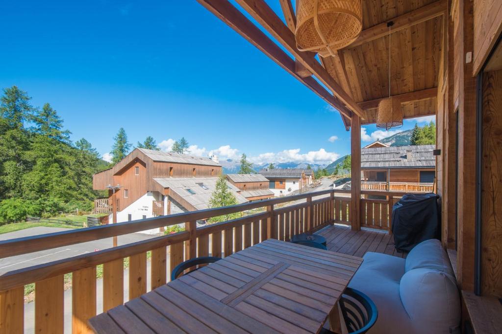 a balcony with a couch and a view of the mountains at Le Refuge des Castorres - Chalet moderne in Les Orres