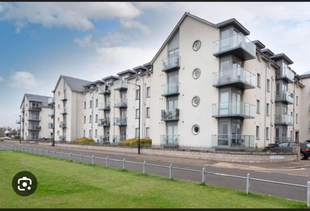 a large white apartment building on a street at A glimpse of the championship in Carnoustie