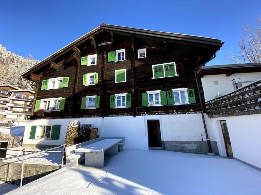 um grande edifício de madeira com neve no chão em Ferienhaus Casa Pistur em Disentis