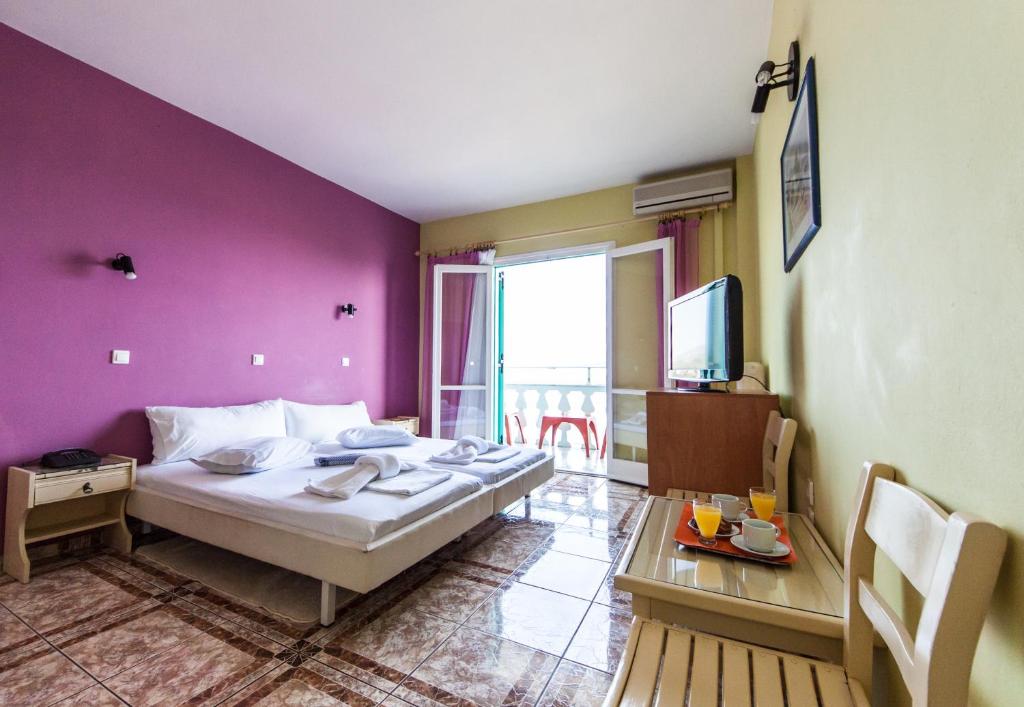 a bedroom with a bed and a table and a tv at Kokkari Beach Hotel in Kokkari