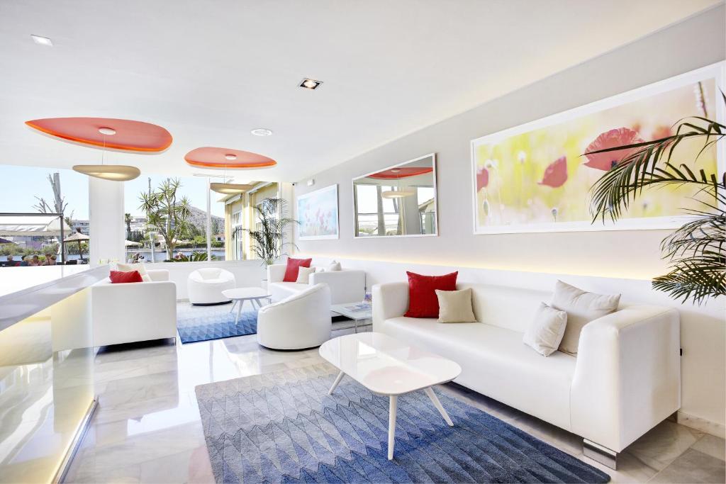 a living room with white furniture and red pillows at Grupotel Amapola in Playa de Muro