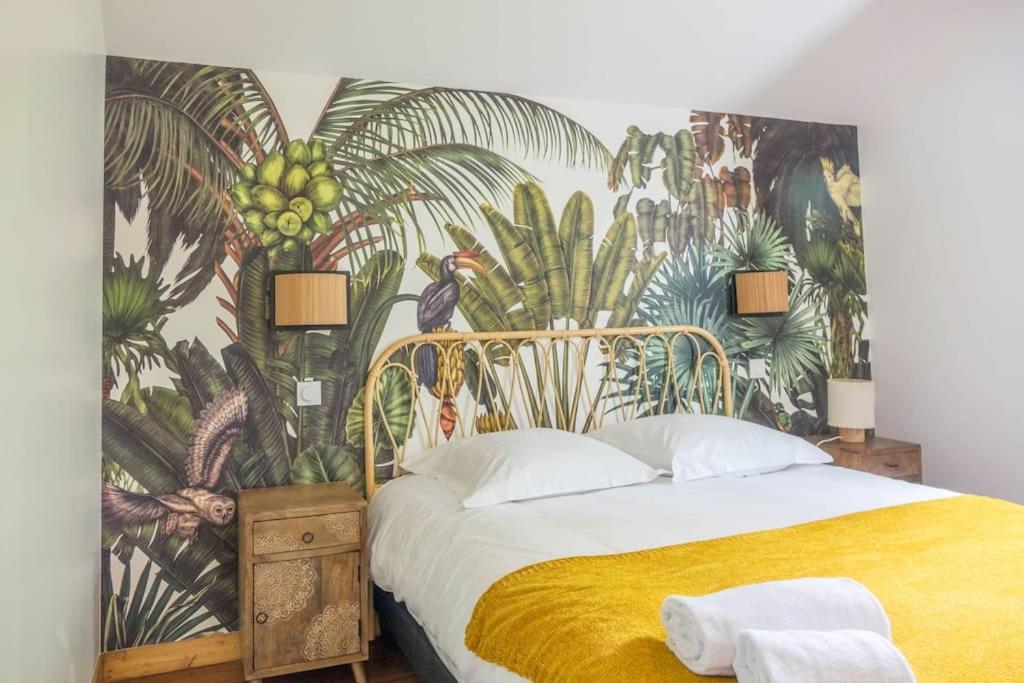 a bedroom with a large bed with a tropical wallpaper at La Petite Maison *T3* accès direct Loiret +Parking in Saint-Hilaire-Saint-Mesmin