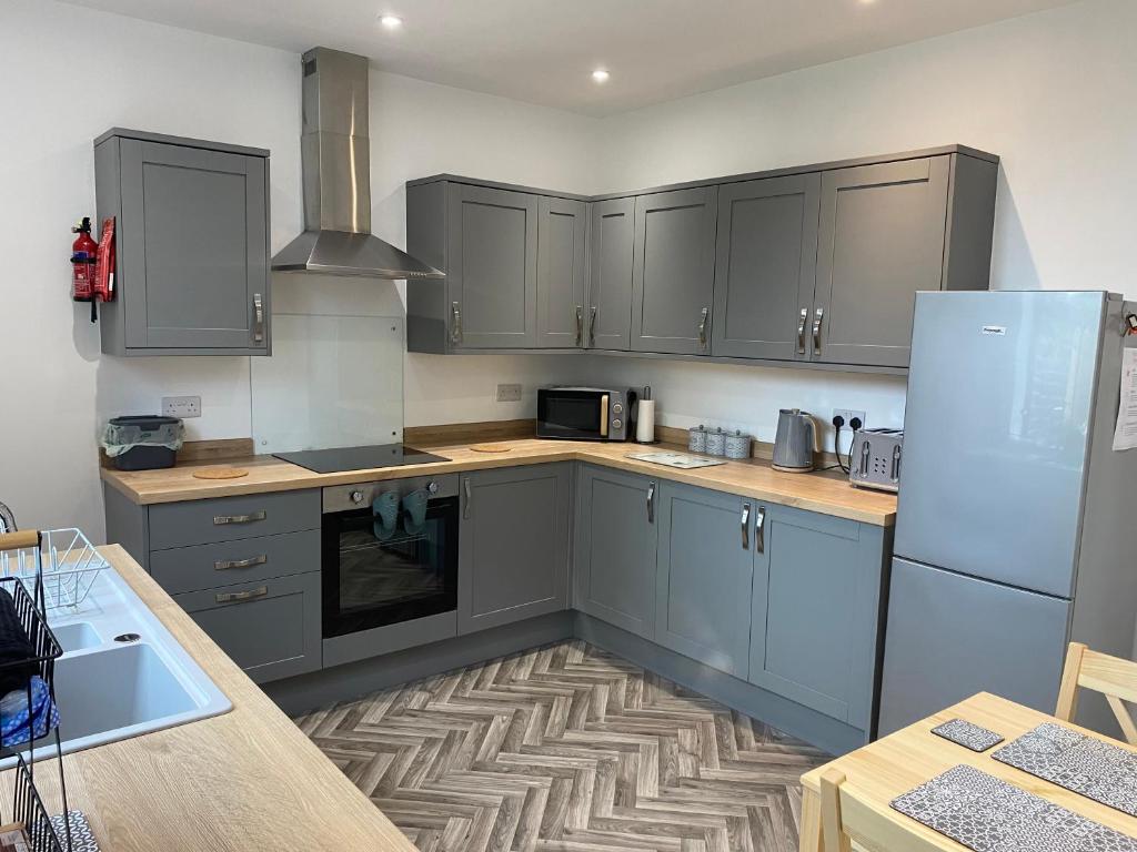 a kitchen with gray cabinets and a refrigerator at House In Padfield in Tintwistle