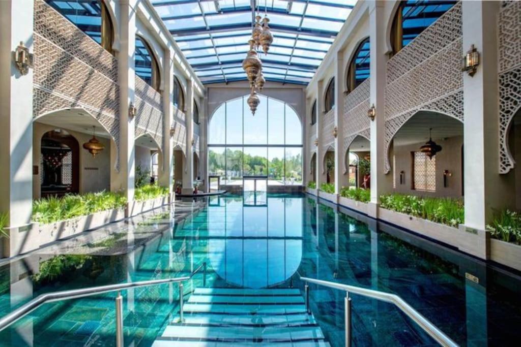 een groot binnenzwembad in een gebouw met een glazen plafond bij Villa June Rosy in Wijchen