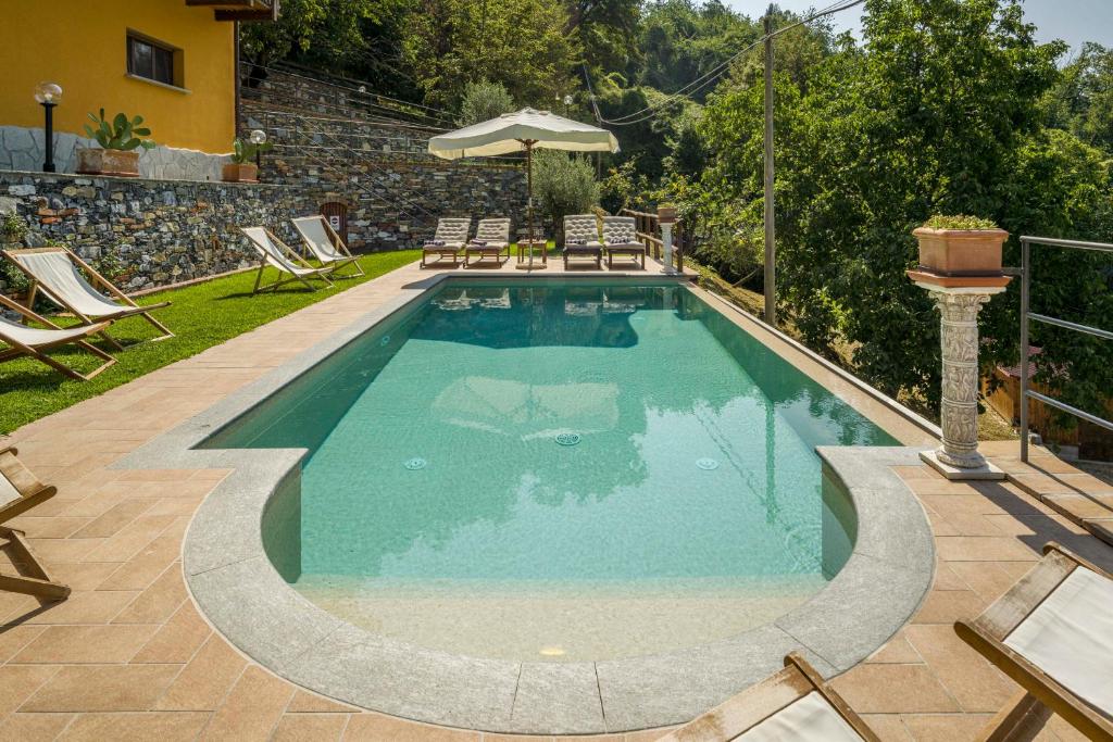 a swimming pool in a yard with chairs and an umbrella at Casa Aurora in Uscio