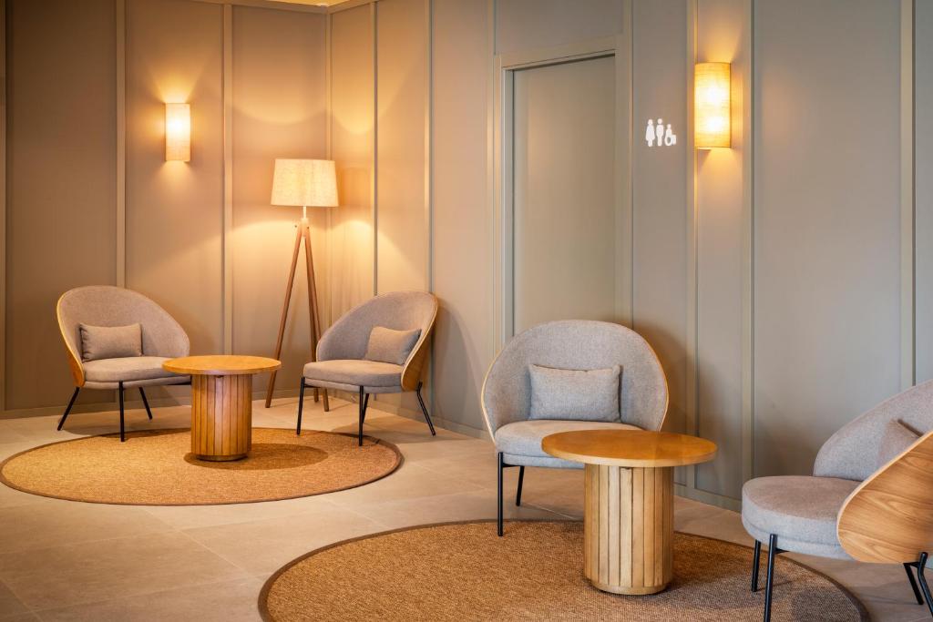 una sala de espera con sillas, mesas y una lámpara en B&B HOTEL Vila do Conde en Vila do Conde