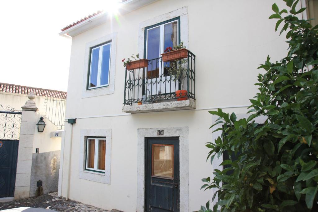 ein weißes Haus mit einer schwarzen Tür und einem Balkon in der Unterkunft São Vicente House in Lissabon