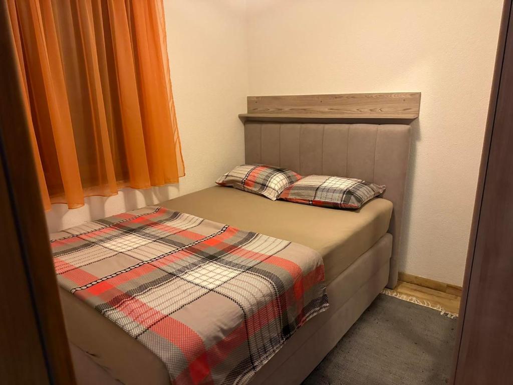 a small bed in a bedroom with an orange curtain at Apartman Edi in Nin