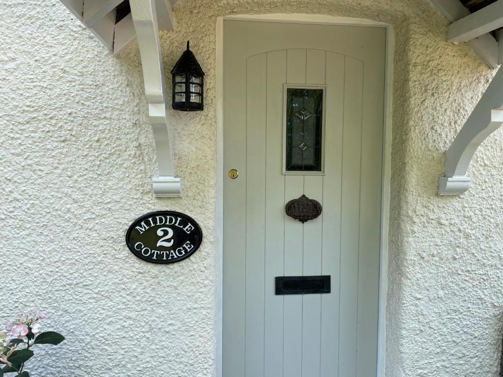 Una puerta blanca de una casa con un cartel. en Charming country cottage in quiet rural setting, 