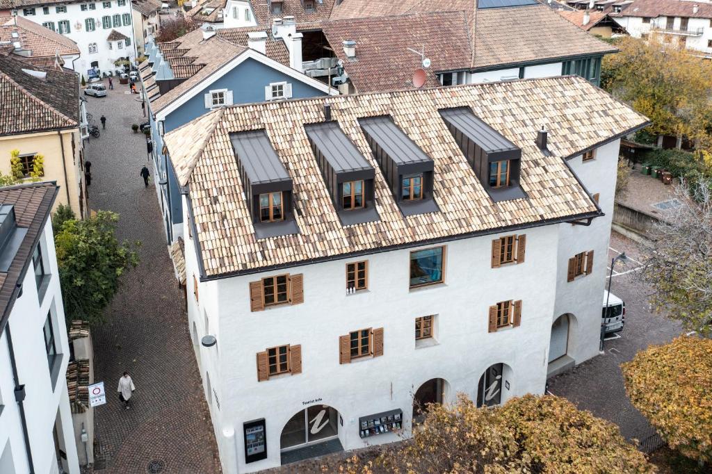 una vista aérea de un edificio blanco con techo de azulejos en Schmitte am Sonnenwirtsplatz in Eppan an der Weinstraße - perfect starting point for hikes and bike tours, en Appiano sulla Strada del Vino