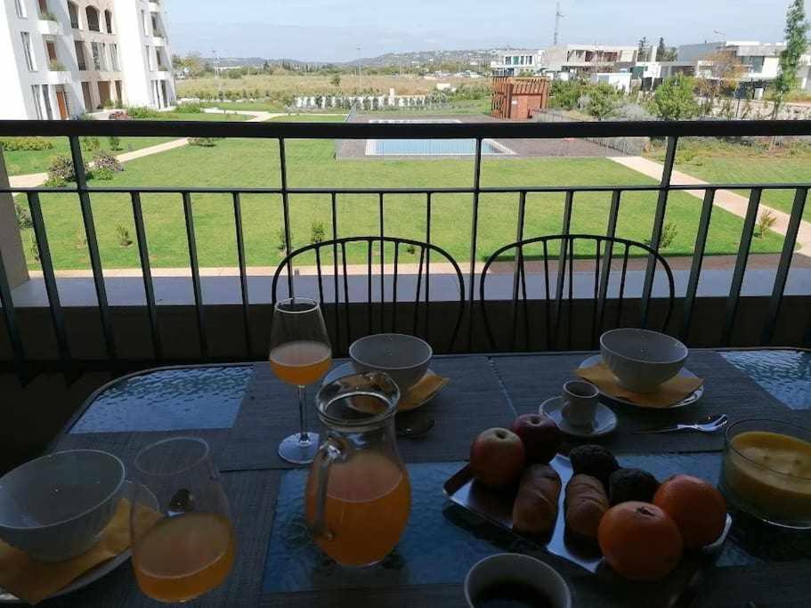 een tafel met een glas sinaasappelsap en eten erop bij Gardens Pool T2 Golf piscina e parking in Quarteira
