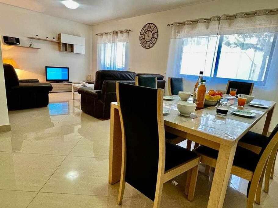 a dining room and living room with a table and chairs at Mar e Sol by - T3 , wi-fi e estacionamento in Quarteira
