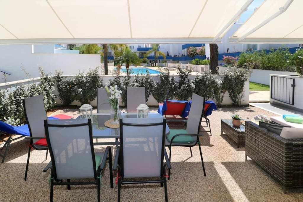 Un patio con mesa y sillas y una piscina. en Anzol By FHR, en Quarteira