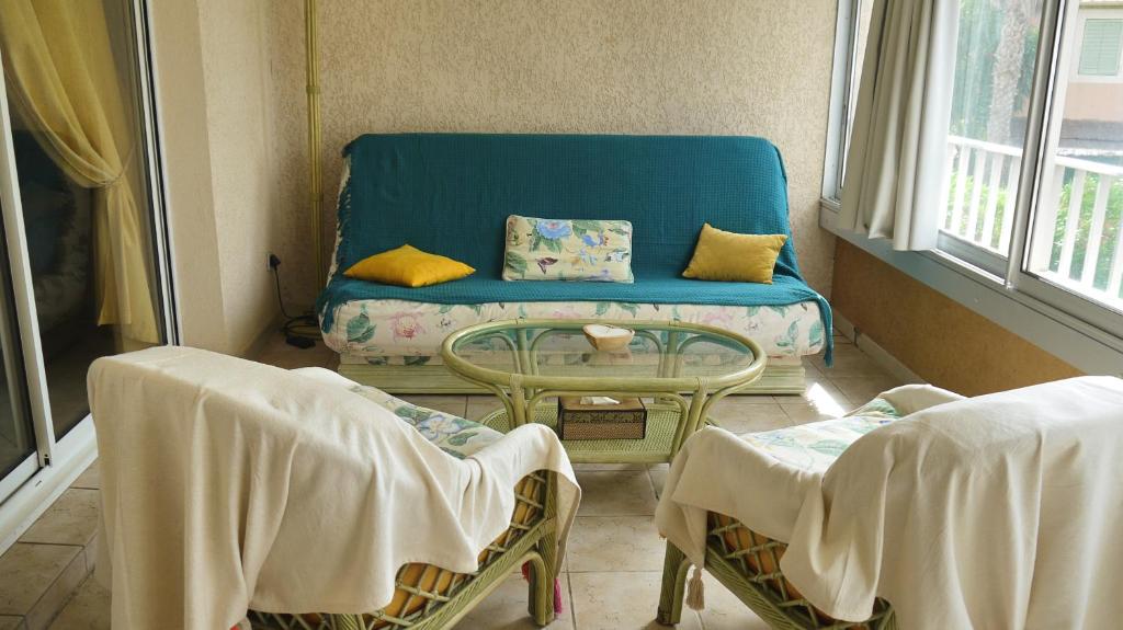 un soggiorno con divano blu e tavolo di Appartement avec piscine proche de la mer a La Londe-les-Maures