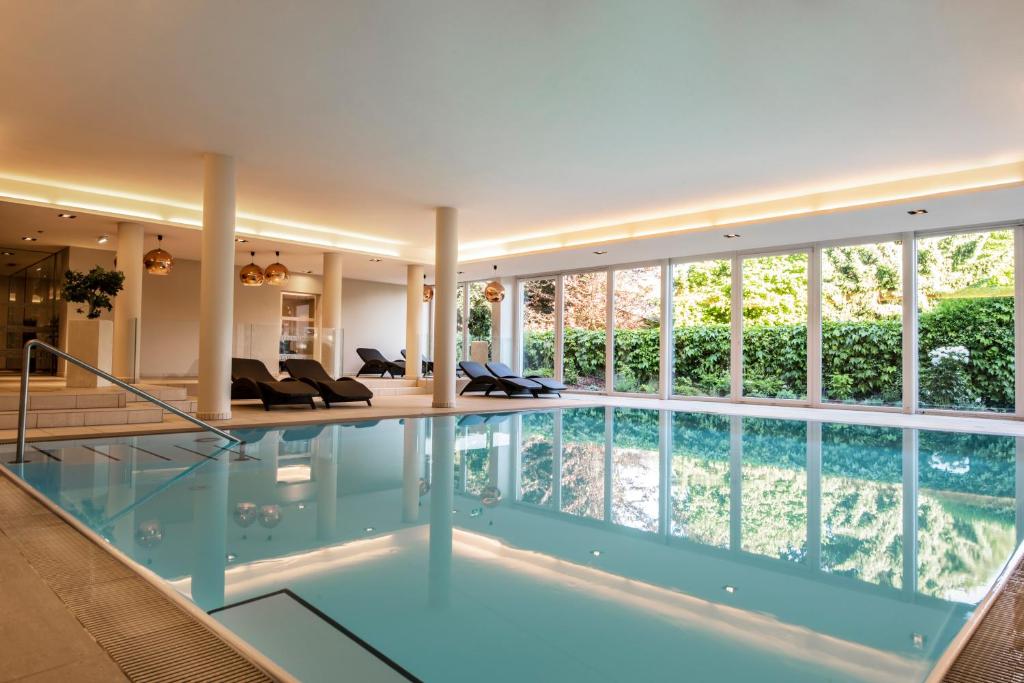a swimming pool in a house with a large window at Apart Hotel Legendär in Steindorf am Ossiacher See