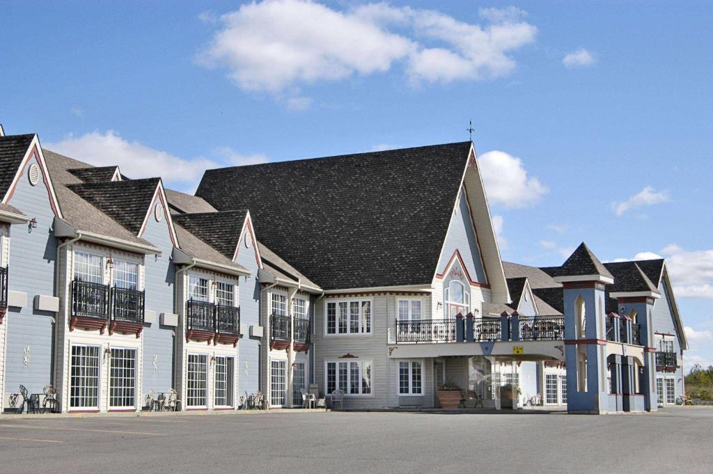 une grande maison blanche avec un toit noir dans l'établissement Days Inn by Wyndham Edmundston, à Edmundston