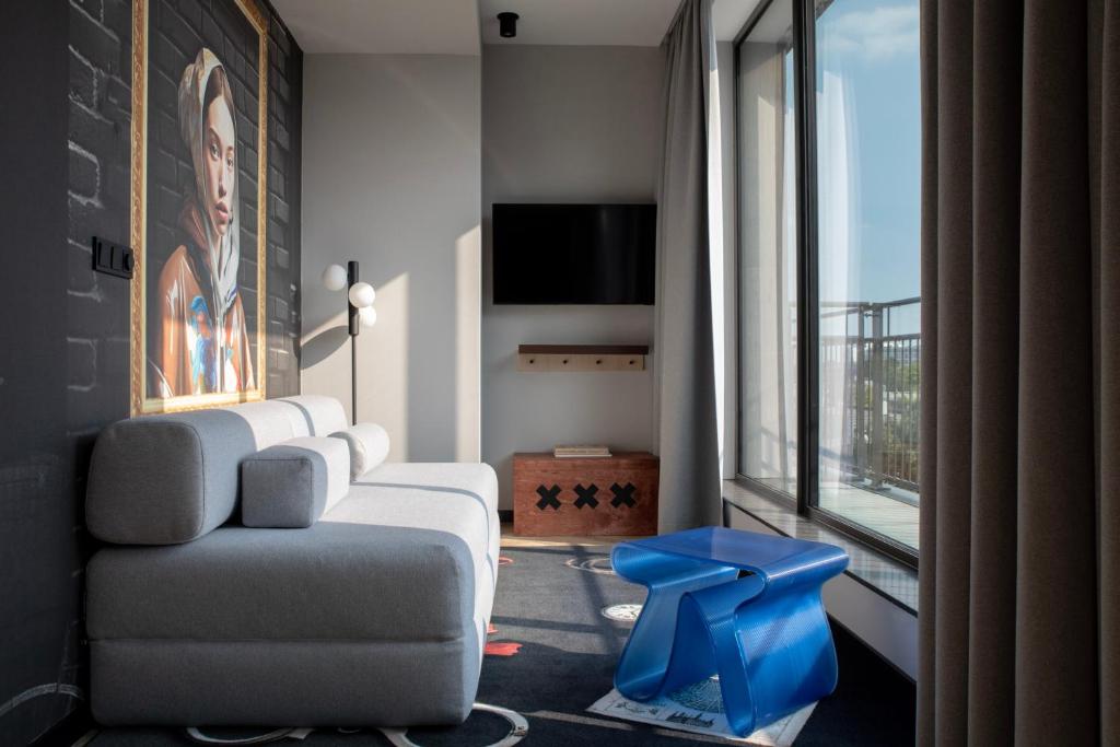 een woonkamer met een bank, een stoel en een raam bij Bob W Amsterdam Noord in Amsterdam