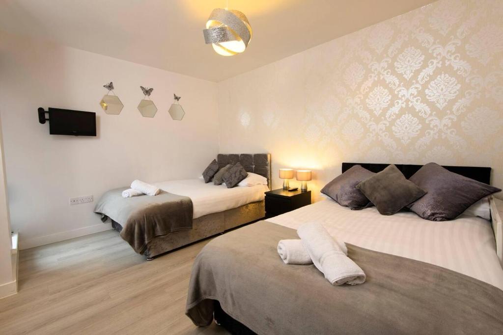 a bedroom with two beds and a tv on the wall at 1 bed apartment close to Football Grounds in Liverpool