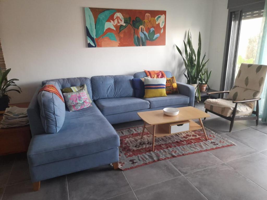 a living room with a blue couch and a table at דירה נעימה בבנין הקהילתי הירוק in Harish