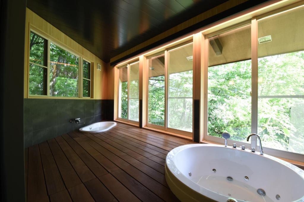 a bathroom with a large tub and windows at ユニテ蔵王ジョーニダ リゾート in Yamagata